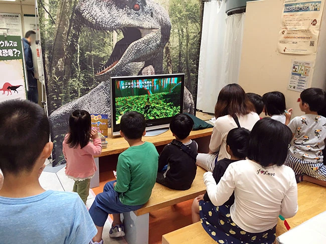 備え付けのディスプレイで飛び出す３Ｄ恐竜展映像を視聴。スクリーンがなくても、この方法ならイベントを行えます。