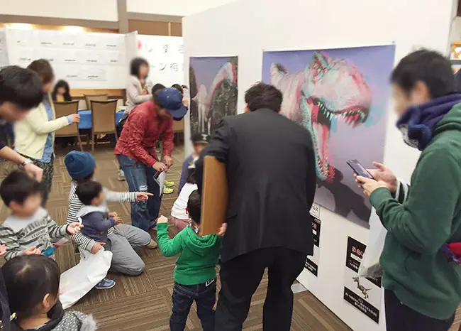 飛び出す３Ｄ恐竜展ポスターを楽しむお子様。