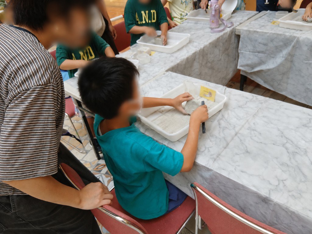専用トレイで化石を掘り出す体験。夢中になって取り組むお子様の姿が見られました。
