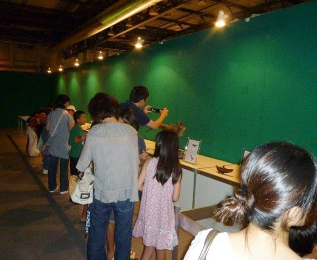 ティラノサウルス精巧ジオラマの写真におさめるお父さん。