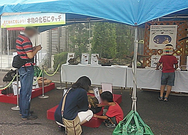 巨大なアパトサウルスの骨にタッチする親子