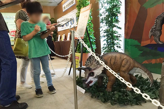 謎解きに夢中な男の子とトリケラトプスフィギュア